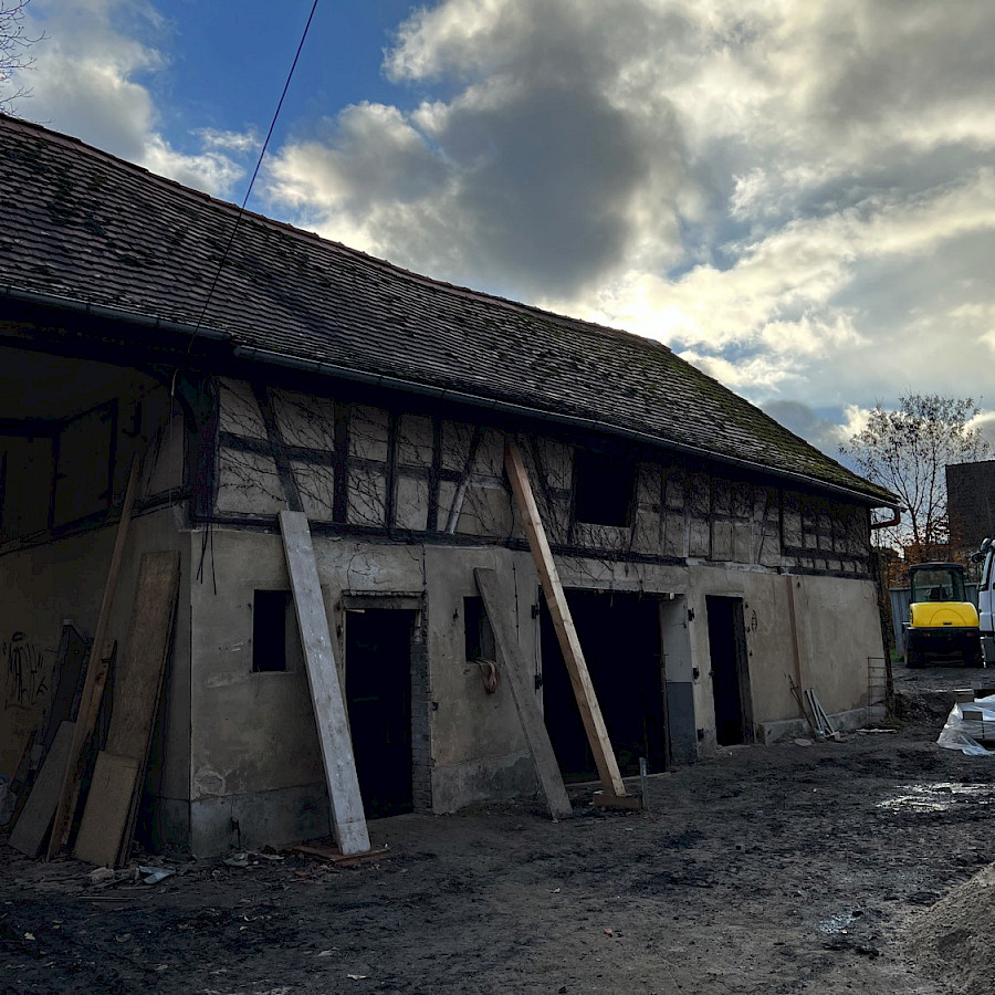 Scheunenhaus mit Balken und Baufahrzeug davor