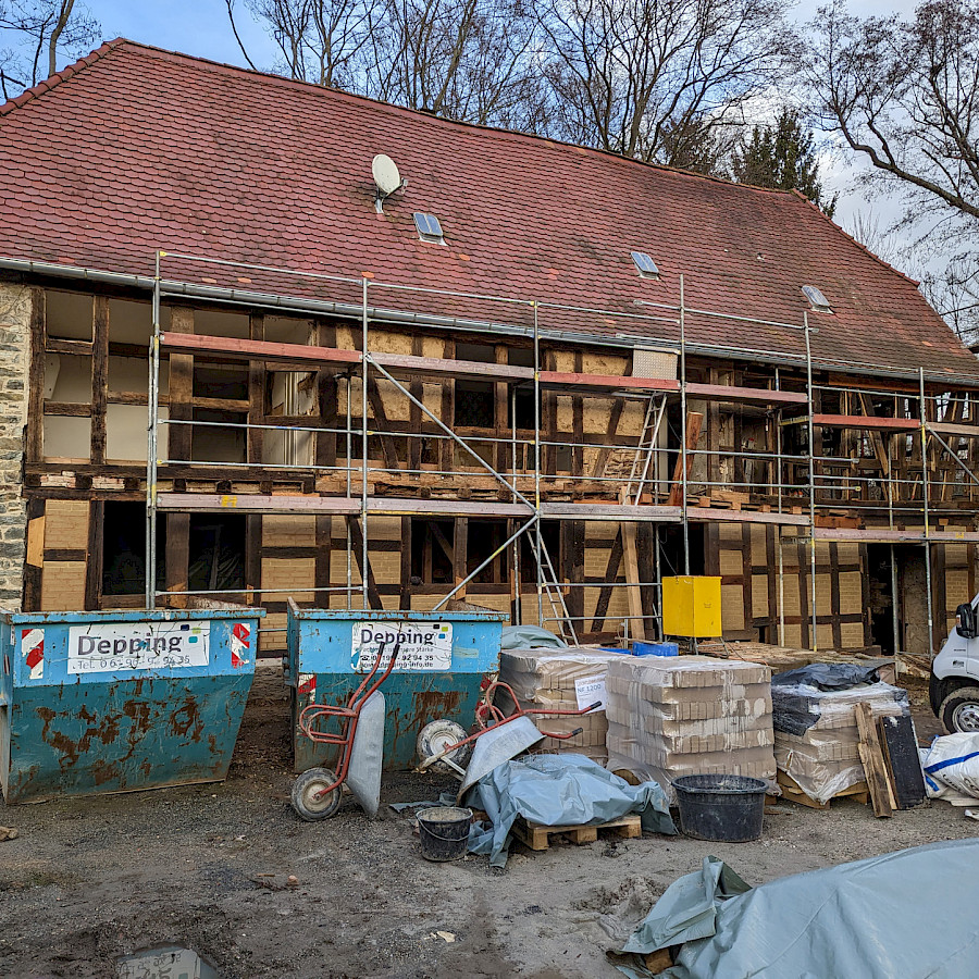 Haupthaus mit Baugerüst, davor Baumaterial, Container und Lieferwagen
