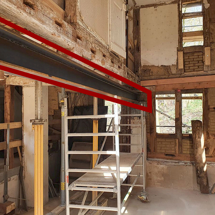 Blick in den zukünftigen Gastraum mit rot kenntlich gemachten neu eingebautem Stahlträger, darunter ein Baugerüst