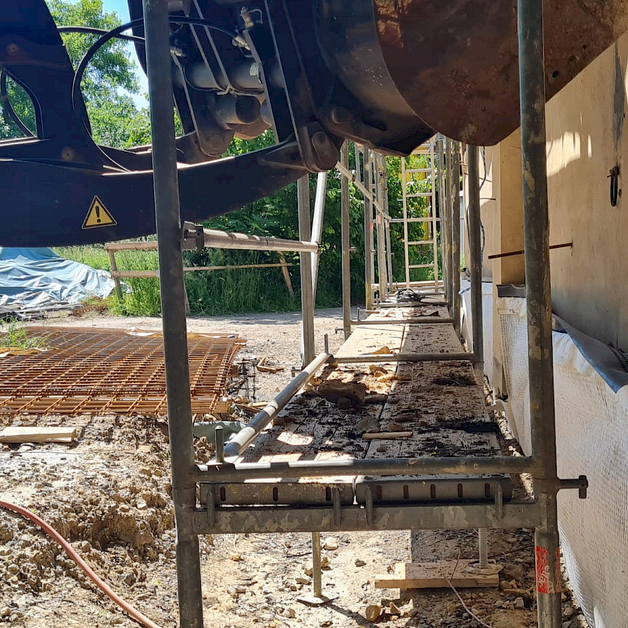 Detail des Scheunenhauses mit Gerüst und Bagger