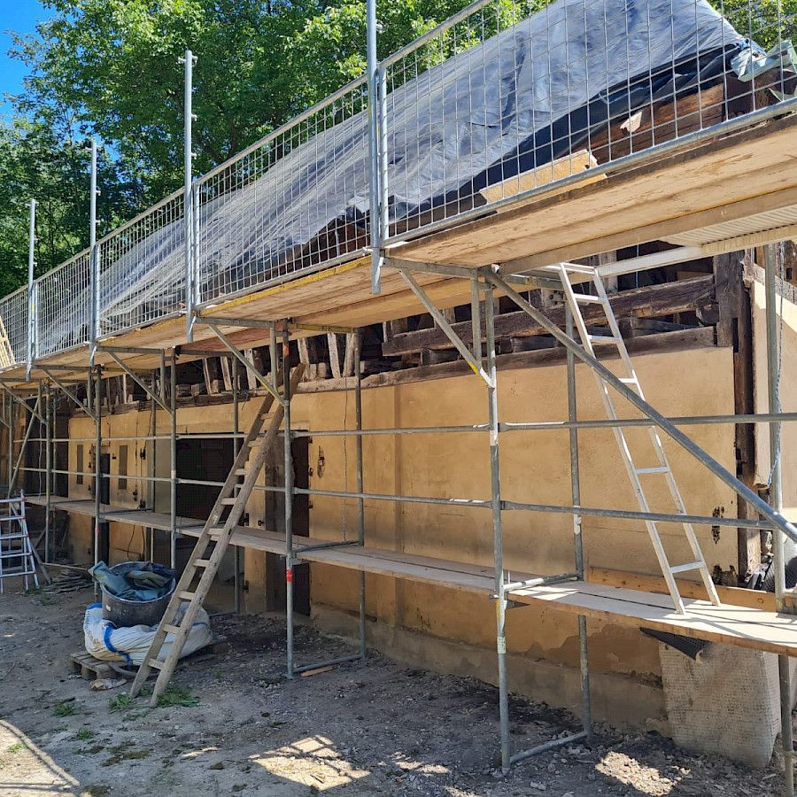 Scheunenhaus mit Gerüst und Plane über dem freigelegtem Dachstuhl, Blick vom Hof