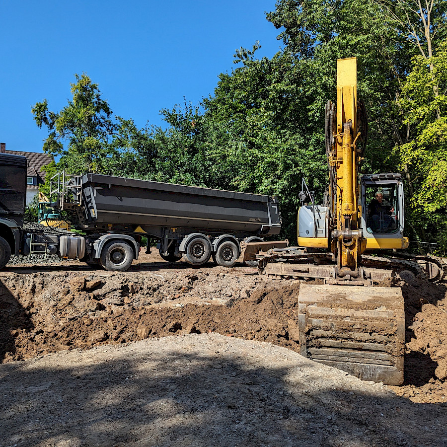 Blick aus der Baugrube auf einen LKW und einen Bagger