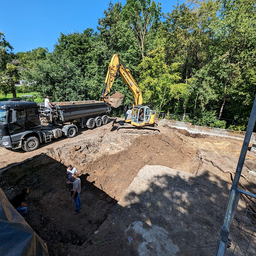 Blick auf die Baugrube mit LKW und Bagger