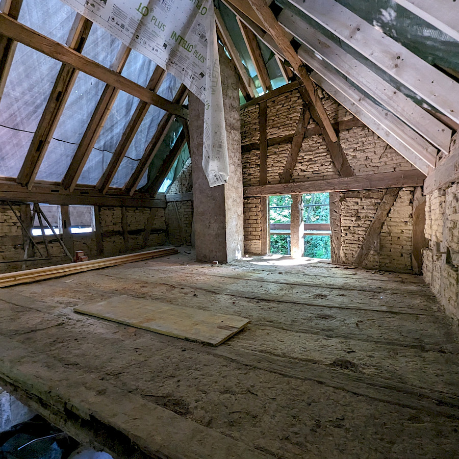 Dachgeschoss des Scheunenhauses mit freigelegtem Dachstuhl und Plane drüber