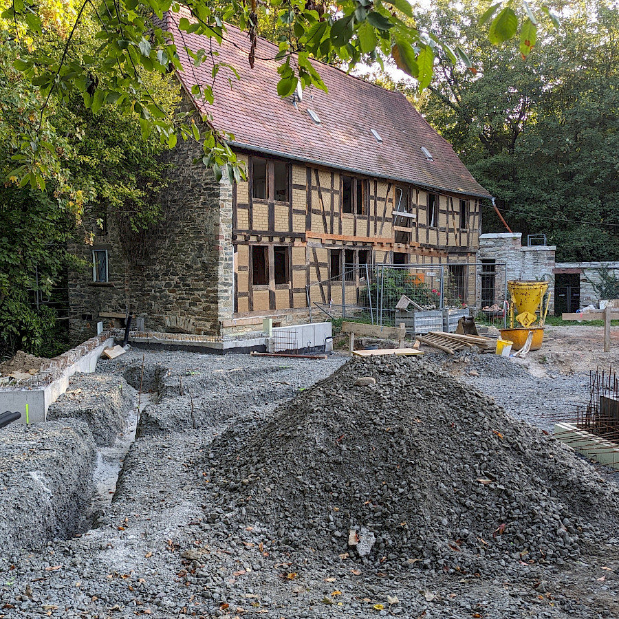 Blick mit Baugrube und Schotterberg auf das Hauptgebäude