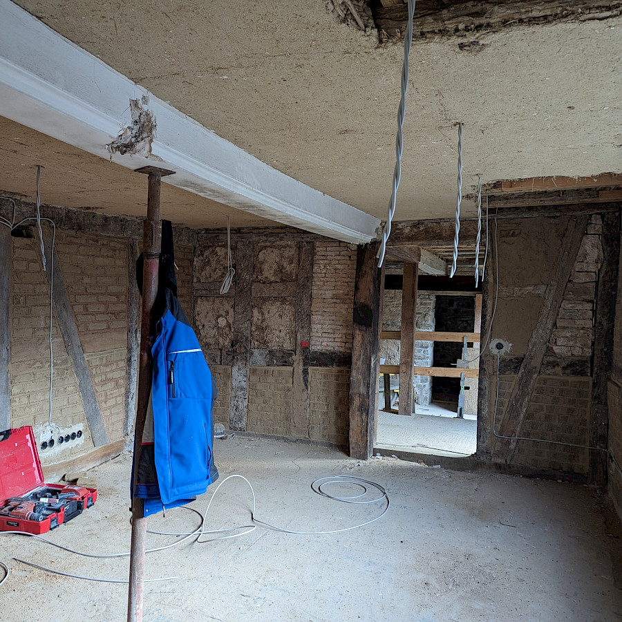 Raum im Scheunenhaus mit abgestütztem Deckenbalken und Blick auf den Eingang zum Mühlengelände