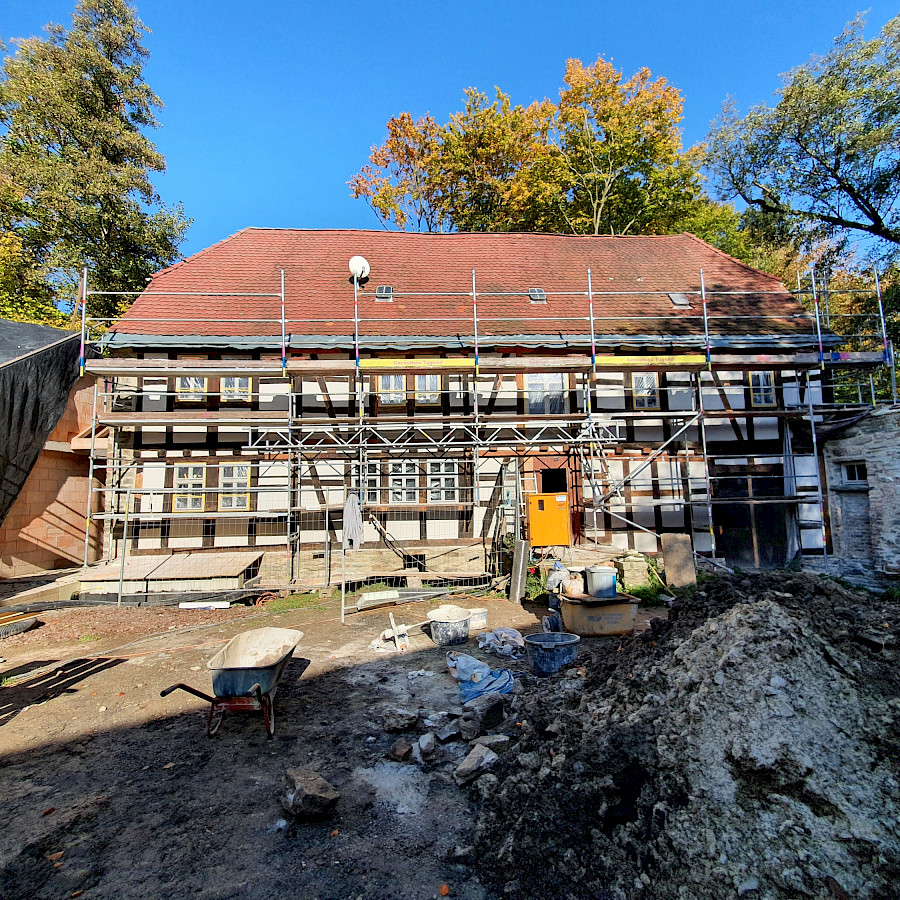 Blick über den Hof auf das neue verputzte Haupthaus mit Baugerüst