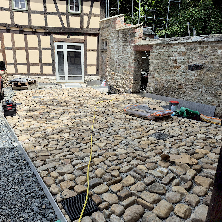 Neu gelegte Pflastersteine an der Begrenzungsmauer vor dem Haupthaus